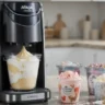 Ninja Creami ice cream maker with colorful ice cream pints and toppings on a kitchen counter.