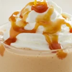 Glass of creamy Caramel Milkshake Slushi topped with whipped cream and caramel drizzle