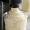 Close-up of a Ninja Creami machine processing vanilla ice cream with a creamy texture.